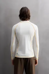 Camiseta de surf compresiva slim fit confeccionada en tejido técnico muy elástico y ligero. Con factor de protección ultravioleta 40+, cuello subido, manga larga, costuras planas y acabados combinados a contraste.