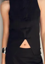 Vestido largo negro con chaleco incorporado, sin mangas y con abertura triangular en el abdomen.