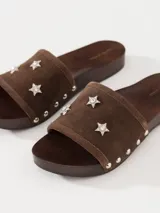 Zueco marrón de cuero vacuno descarne con base de madera y detalles de tachas. La capellada lleva apliques de estrellas con strass.