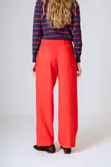 Pantalón negro de corte ancho y tiro alto, con pinzas en la cintura y bolsillos laterales.
