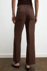 Jeans de tiro alto, pierna ancha y largo al tobillo, en denim celeste claro con efecto lavado. Presenta costura marcada en el centro de cada pierna y cierre frontal con cremallera y botón.