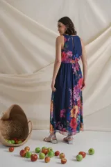 Vestido largo de gasa estampada con flores en tonos lila y rojo sobre fondo azul. Tiene cintura elastizada y cuello halter.