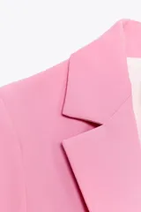 Blazer entallada color rosa, confeccionada en mezcla de viscosa. Tiene cuello solapa con muescas, manga larga, bolsillos con solapa en el delantero, forro interior a contraste y cierre frontal con botón.
