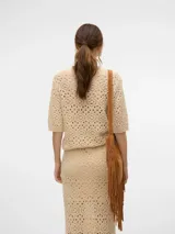 Suéter de punto calado color beige, con cuello redondo y mangas cortas. Corte estándar y tejido suave.