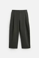 Pantalón relaxed fit color verde oscuro, con pliegues en la parte delantera, bolsillos laterales y traseros de ojal. Cierre frontal con cremallera y botón.