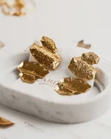 Par de aros colgantes dorados con cuatro dijes metálicos móviles con forma de hojas o gotas brillantes. Fabricados en acero quirúrgico con baño de oro.