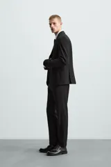 Pantalón de vestir azul marino, de corte slim fit, con bolsillos laterales y traseros. Se ajusta a la cintura con cinturón de cuero marrón.