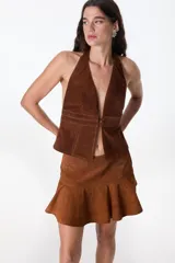 Top halter de cuero color beige, con escote profundo en V y cierre frontal con tiras horizontales.