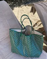 Bolso tipo tote bag con estampado geométrico en tonos verde y blanco, con detalles y asas en cuero sintético verde.