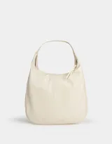 Cartera saca hobo color crema de cuerina, con asa de hombro y cierre superior con tirador.