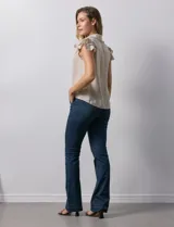 Camisa color beige de satén, con cuello con solapa y escote en V. Tiene una apertura central con botones y sisas con volados.