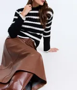 Suéter de punto para mujer con diseño a rayas horizontales en blanco y negro. Presenta una textura acanalada, cuello alto y mangas largas.