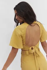 Top de lino color amarillo con mangas cortas y espalda abierta, diseño versátil.