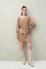 Vestido corto negro de punto con brillo sutil, mangas largas amplias, falda ajustada y lazo frontal en la cintura.