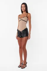 Short negro de cuerina con cierre diagonal desmontable, tiro medio y broches snap en el delantero.