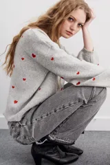 Sweater gris melange de calce holgado con corazones bordados en color rojo, y mangas balloon.