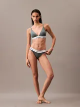 Conjunto de ropa interior Calvin Klein, modelo Modern Cotton, color gris, compuesto por un corpiño triangular con breteles finos regulables y una bombacha tipo tanga. Ambos con banda elástica blanca con logo de la marca.