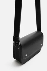 Bandolera negra con acabado grabado, compartimento principal con cierre de solapa imantada, bolsillo interior con cierre y bolsillo frontal con cierre. Asa de hombro ajustable.