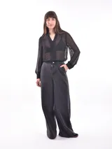 Camisa negra traslúcida con lunares, cuello en V con volados y botones frontales.