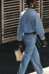 Camisa corta de denim celeste, con cuello solapa, manga larga, bolsillo delantero de plastrón y cierre frontal con botones metálicos.