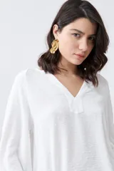 Blusa color crudo con escote en V y mangas largas.