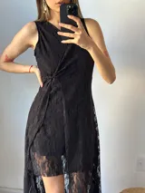 Vestido corto de encaje negro con escote en V, sin mangas y corte irregular.