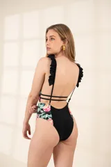 Traje de baño enterizo negro con estampado floral en los laterales y volados en los tirantes.
