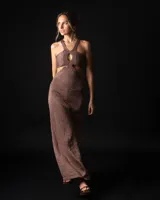 Vestido largo marrón de tejido de punto con lurex, corte ajustado, cuello halter con abertura circular y aberturas laterales en la cintura.