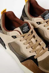 Zapatillas deportivas marrones con detalles en beige, negro y amarillo.