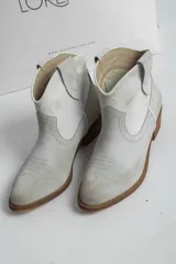 Botines de cuero color gris claro, estilo texano, con puntera fina, caña baja y taco de madera.