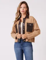 Chaqueta de corte boxy confeccionada en tejido de punto color crema, con detalles en cuero sintético negro en cuello, solapas, cartera central y bolsillos frontales. Presenta cierre frontal con botones metálicos plateados y costuras decorativas visibles.