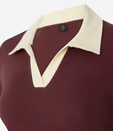 Blusa blanca acanalada de rib con cuello polo negro contrastante y mangas cortas.