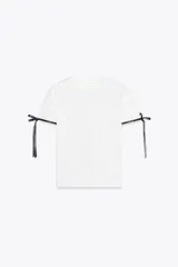 Camiseta blanca de corte recto y manga corta, con cuello redondo y lazos negros en los extremos de las mangas.