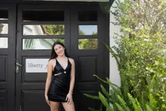 Vestido corto de fiesta color lila metalizado, con escote en V, breteles finos, cut-outs en la cintura y falda ajustada con cordones laterales.