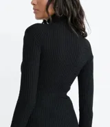 Blusa negra de tejido de punto acanalado con cuello alto y mangas largas.