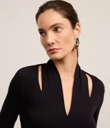 Blusa negra de mangas largas confeccionada en viscosa, con cuello alto, escote V y aberturas en los hombros.