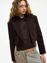 Blazer cropped marrón oscuro con solapa en la parte delantera y camisa desmontable mediante botones. Confeccionado en 97% algodón y 3% elastano.