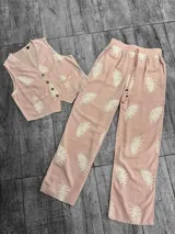 Conjunto blanco con estampado de hojas color borgoña, compuesto por un chaleco con botones y un pantalón de corte recto.