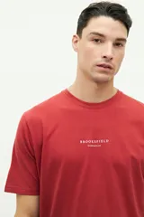 Remera roja de manga corta con cuello redondo y logo de la marca BROOKSFIELD estampado en el pecho.