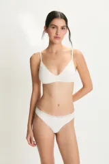 Conjunto de lencería de dos piezas color blanco roto, compuesto por un soutien sin aro con tirantes finos y un borde de encaje festoneado en el escote, y una bombacha tipo bikini con el mismo detalle de encaje en el borde superior.