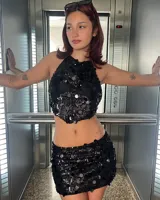 Top corto negro con lentejuelas, escote halter y espalda descubierta.
