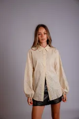 Camisa celeste con estampado de flores blancas, corte clásico, cuello camisero y mangas largas abullonadas.