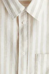 Camisa de manga larga con cuello inglés y bolsillo en el pecho. Diseño a rayas verticales en tonos beige y blanco. Corte estándar.