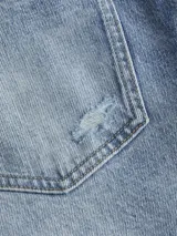 Jean de denim celeste con efecto desgastado y roturas, de corte mom, tiro alto y cinco bolsillos.