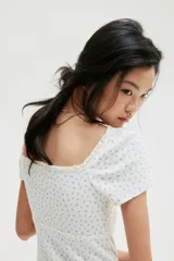 Vestido corto blanco con estampado floral celeste, de punto acanalado con escote corazón ribeteado en encaje y cordón para ajustar en el centro del busto. Modelo de manga corta con cuerpo entallado, copas preformadas y pollera con vuelo.