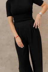 Pantalón palazo negro con lurex, cintura elástica y corte ancho.