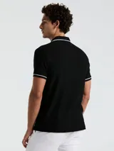 Polo negra de piqué con vivos blancos en cuello y mangas, calce slim fit y logo bordado en el pecho.
