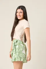 Short pollera con estampado de hojas azules y blancas, diseño cruzado, volados y lazo en la cintura.