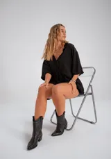 Blusa negra oversize con escote en V y cordones delanteros.