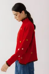 Sweater crudo de tejido de punto con cuello alto con volados y bordados de símbolos de naipes.